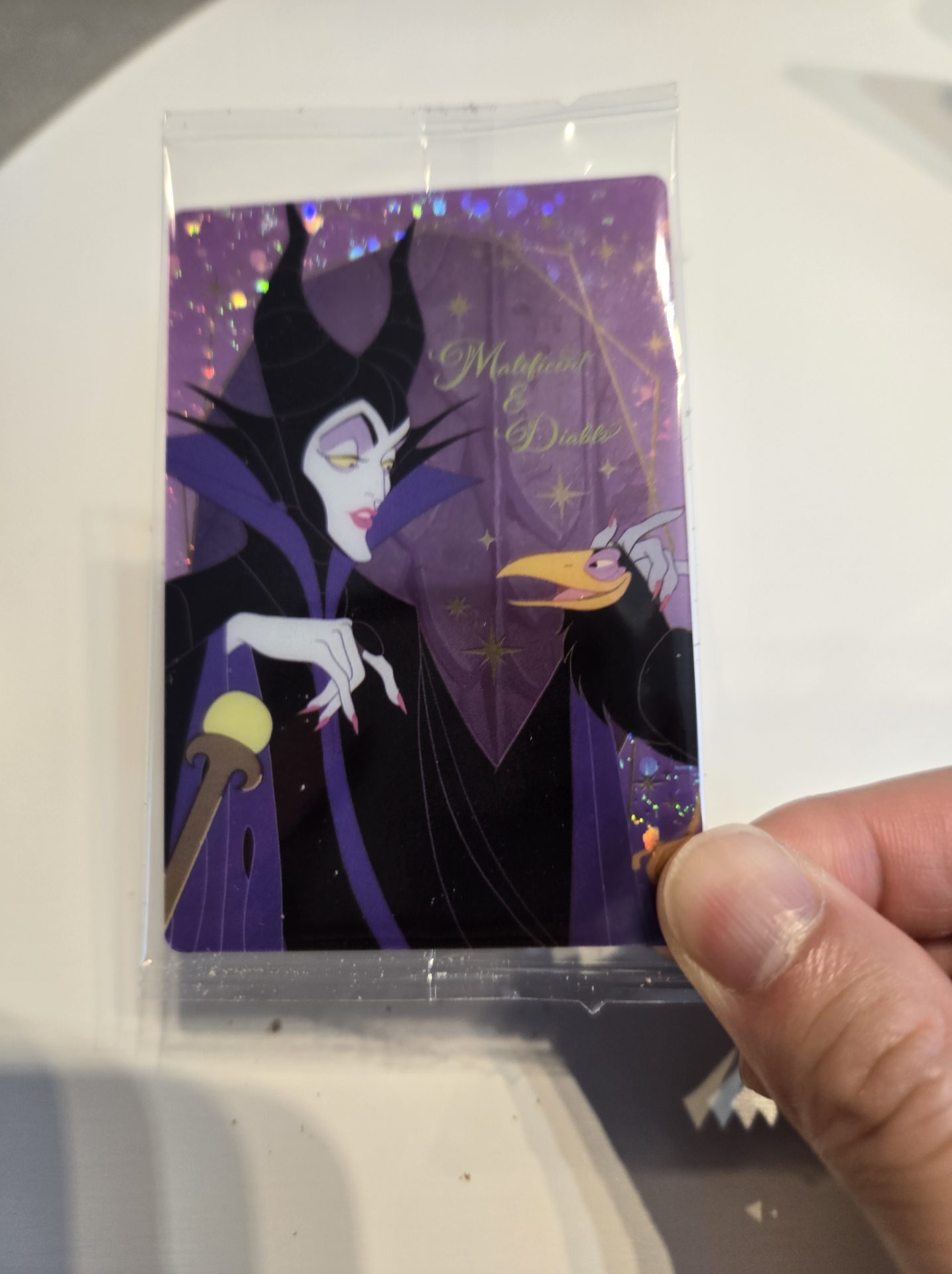 スペシャルアートカード「Maleficent & Diablo」(マレフィセントとディアブロ)の実物写真。紫黒の幻想的な背景にマレフィセントが描かれ、ホロ加工で光っている